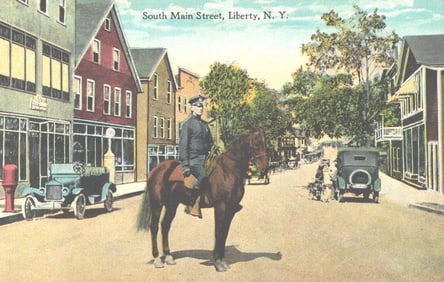 Postcard of South Main Street, Liberty, New York, featuring mounted police officer and cars, c.