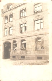 RPPC Real Photo Postcard showing residents looking out windows of a brick apartment building,
