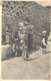 Postcard showing a group of local people and children gathered at the stone Tomb of Lazarus,