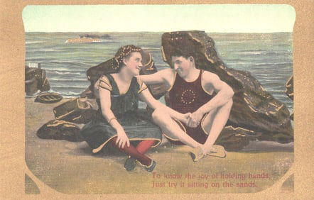 Postcard of a romantic couple in Edwardian swimwear holding hands on a sandy beach, circa 1910s.