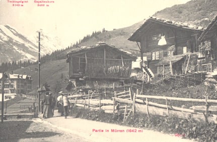 Postcard view of the Swiss mountain village of Mürren with people walking near traditional chalets.