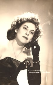 RPPC Real Photo Postcard of a glamorous woman in a strapless gown and black gloves smoking, 1950s.