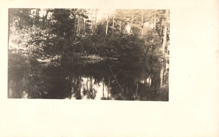 RPPC Real Photo Postcard of a secluded cabin on a wooded shore reflected in still water c. 1910s