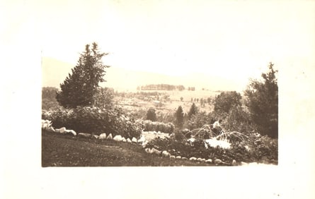 RPPC Real Photo Postcard showing a rural farm valley from a garden with mountains, circa 1910s.