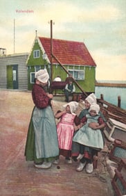 Postcard showing a woman and three young girls in traditional Dutch dress and clogs in Volendam,