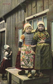 Postcard of three young girls in traditional Dutch folk costumes and clogs in Marken, Netherlands