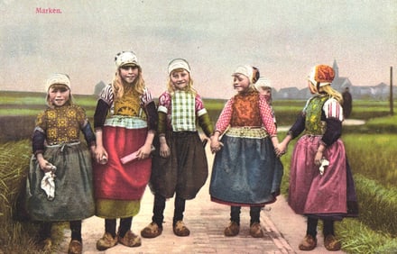 Photochrom postcard of five young Dutch girls in traditional costumes holding hands on a path,
