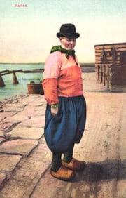Photochrome postcard of a Dutch man in traditional costume with wooden clogs on a stone quay in