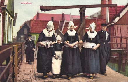Photochrom postcard showing a family in traditional Dutch costumes walking across a bridge in