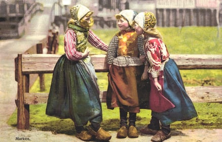Photochromie postcard showing three girls in traditional Dutch folk costumes with clogs from Marken.