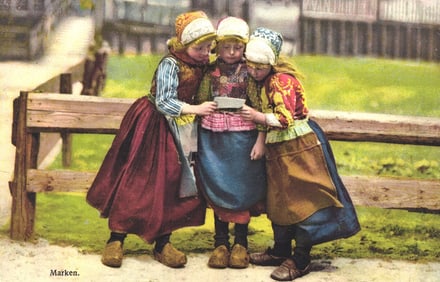 Early 1900s photochrome postcard of three Dutch girls in traditional folk dress in Marken, Holland.