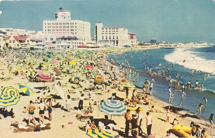 Postcard of a crowded day at Santa Monica Beach, California showing sunbathers and colorful