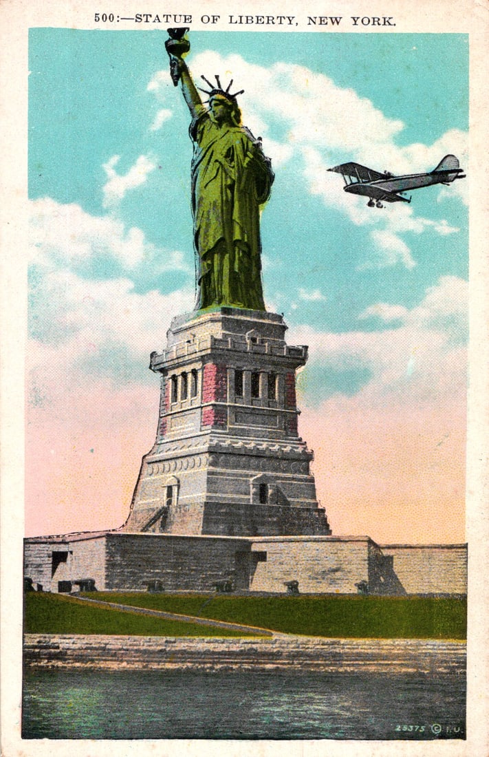 Postcard of the Statue of Liberty in New York Harbor with an early biplane flying past c. 1910s-20s (1 of 2)
