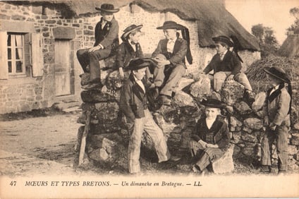 Postcard depicting young Breton boys in traditional costumes on a stone wall in Brittany, France.