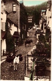 RPPC Real Photo Postcard of donkeys on the steep cobbled High Street in Clovelly, Devon, England.