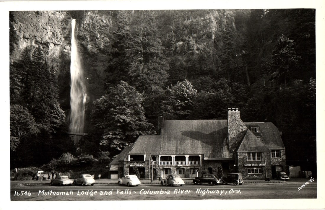 Vintage Multnomah Lodge and Falls, Columbia River Highway, Oregon, black and white photographic: A black and white photographic postcard depicts Multnomah Falls cascading down a sheer rock face to the left, with the large stone Multnomah Lodge situated prominently in the foreground to the right. 