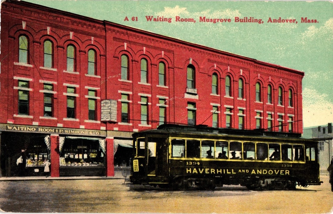 Early 20th Century Postcard: Musgrove Building, P. Simeon & Co. and Streetcar, Andover,: A prominent three-story red brick building, identified as the Musgrove Building, features multiple arched windows on its upper floors. The ground floor displays signage for "WAITING ROOM P. SIMEON & C