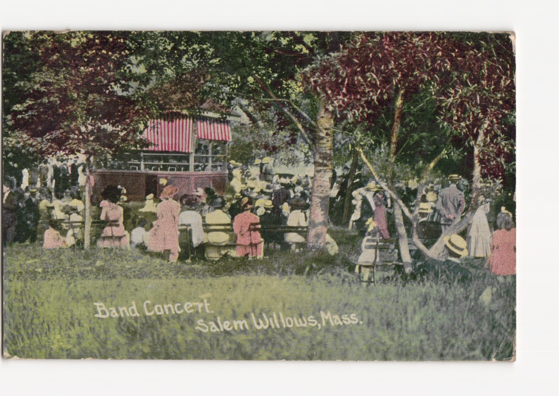 Outdoor Band Concert, Salem Willows, Massachusetts, c. 1911, Hand-Colored Lithograph Postcard: An outdoor band concert scene depicts numerous individuals, primarily women in early 20th-century attire, seated on benches and standing in a park-like setting. They face a multi-level building with a