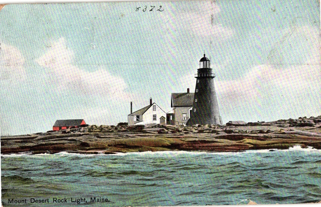 Early 20th-century postcard depicting Mount Desert Rock Light, Maine, with adjacent structures.: Mount Desert Rock Light, Maine, is depicted on a rocky island with several adjacent buildings under a cloudy sky. The lighthouse is a prominent dark, conical tower with a lantern room at its apex. To 