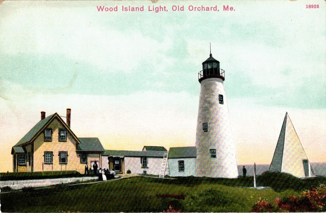 Wood Island Light, Old Orchard, Maine, with Lighthouse, Buildings, and People, Early 20th Century: A prominent white conical lighthouse with a black lantern room stands to the right, adjacent to a complex of buildings. To the left is a two-story clapboard house with a peaked roof and multiple windo