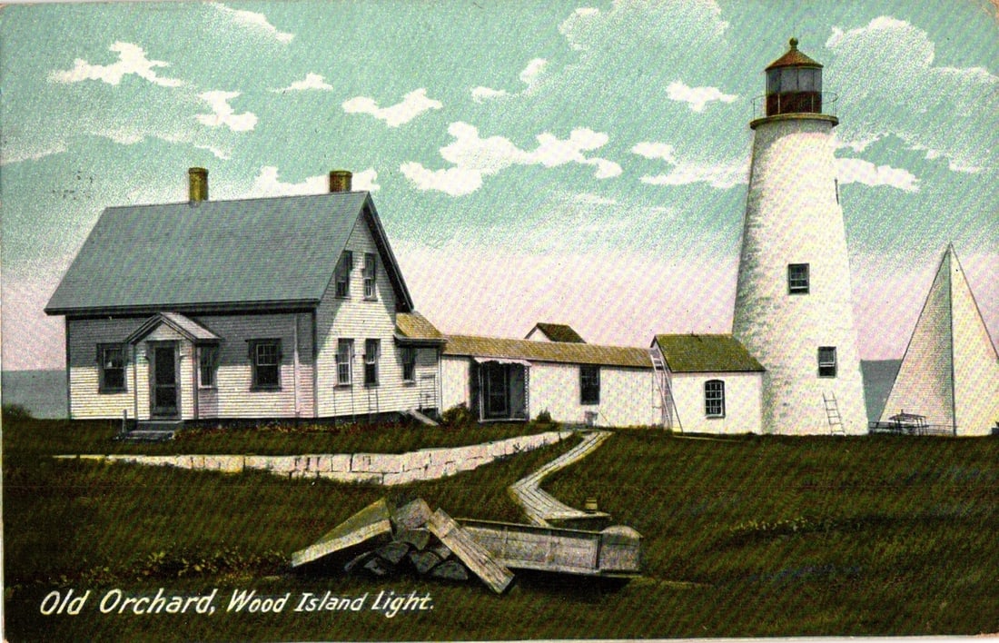 Vintage postcard depicting Wood Island Lighthouse and keepers' residence in Old Orchard, Maine,: A chromolithograph postcard features a scenic view of the Wood Island Light station. The tall, white cylindrical lighthouse with a dark cap stands prominently on the right, flanked by several white cl
