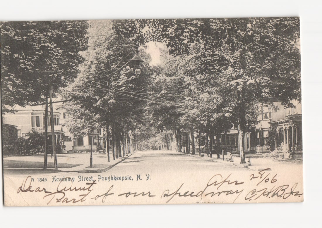Early 20th Century Postcard: Academy Street, Poughkeepsie, N.Y. - Tree-Lined Residential View: A wide street, Academy Street in Poughkeepsie, New York, is depicted, lined on both sides by mature, leafy trees forming a dense canopy overhead. Residential houses with gabled roofs and porches are v