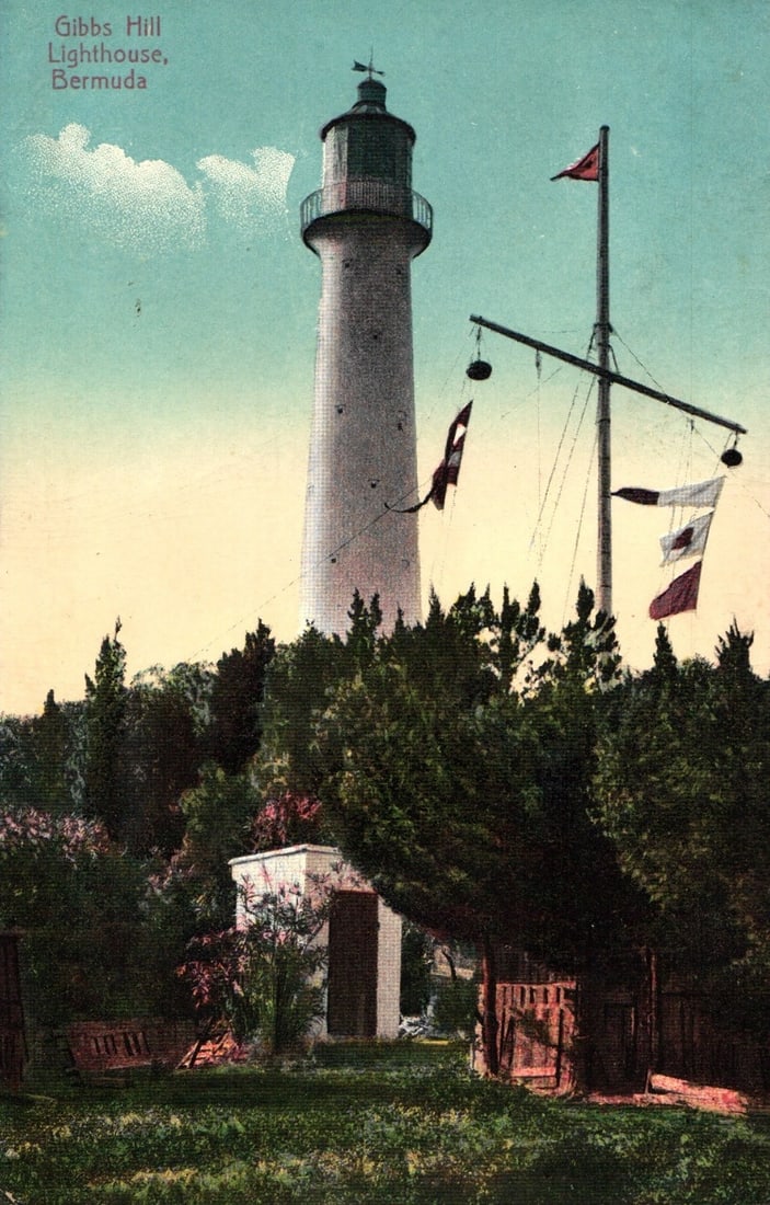 Detailed Chromolithograph Postcard of Gibbs Hill Lighthouse with Signal Mast, Bermuda.: The primary subject is a chromolithograph depiction of Gibbs Hill Lighthouse in Bermuda, a tall, tapering white tower with a dark lantern room and cap. To its right, a tall signal mast flies several f