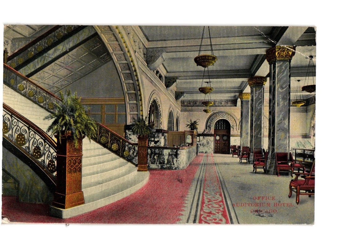 Auditorium Hotel, Chicago: Grand Lobby Interior with Staircase and Office Area postcard: A grand interior view of what is identified as the Auditorium Hotel in Chicago. The foreground features a sweeping staircase with a richly ornamented railing and patterned newel posts, each topped wit