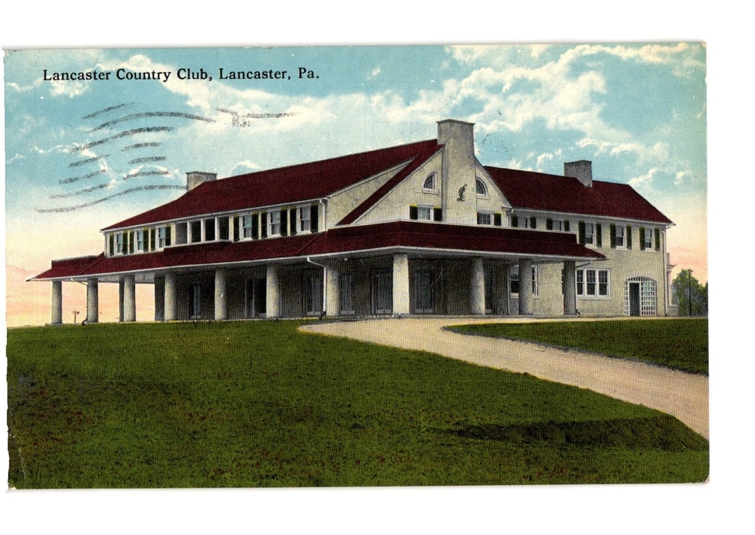 Lancaster Country Club, Lancaster, Pennsylvania - 1914 early 20th century architectural postcard.: A large, multi-story building featuring a prominent red roof and numerous white-framed windows is centrally depicted. The structure includes a long, columned veranda extending along its front, with a 