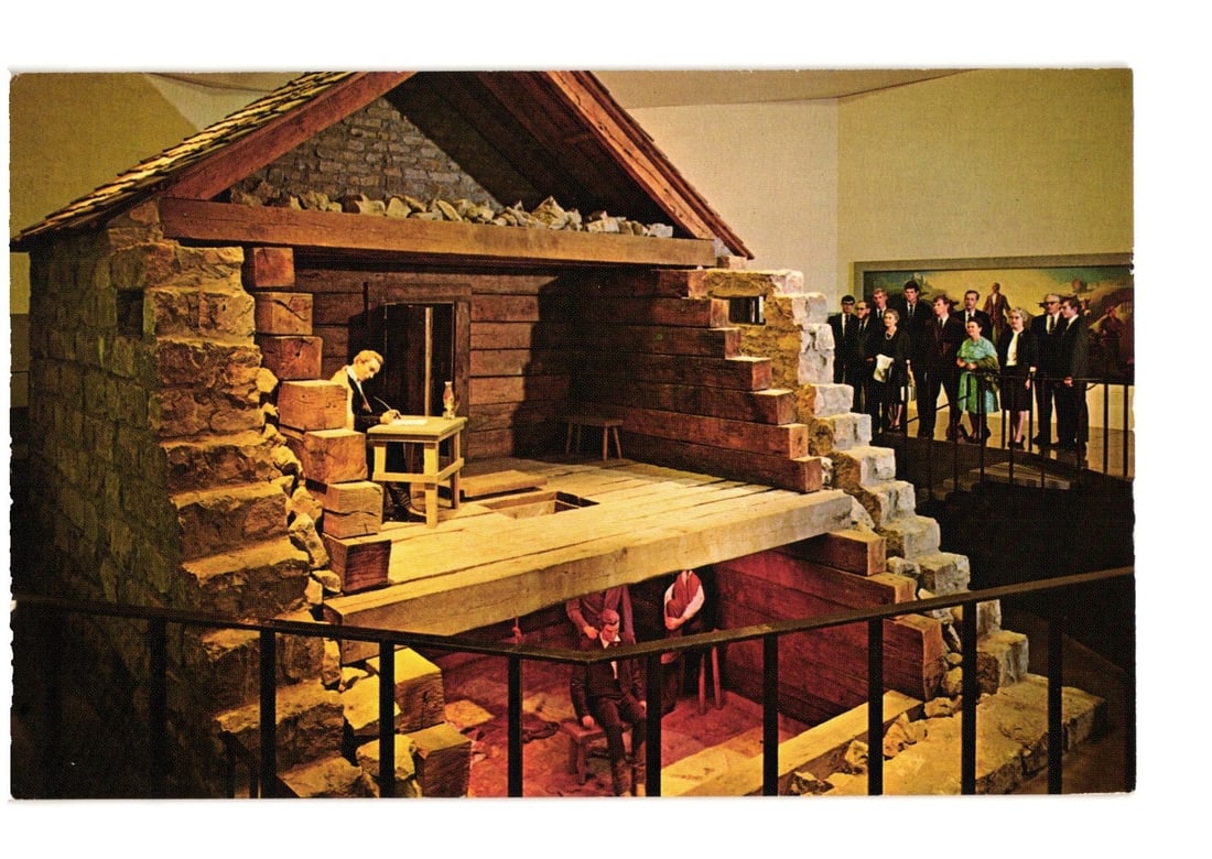 Historic Liberty Jail museum exhibit cutaway view with figures, Missouri, color postcard.: A color photographic image displays a detailed cutaway exhibit of Historic Liberty Jail. The structure, constructed with stone and log, reveals two interior levels. On the upper level, a figure is sea