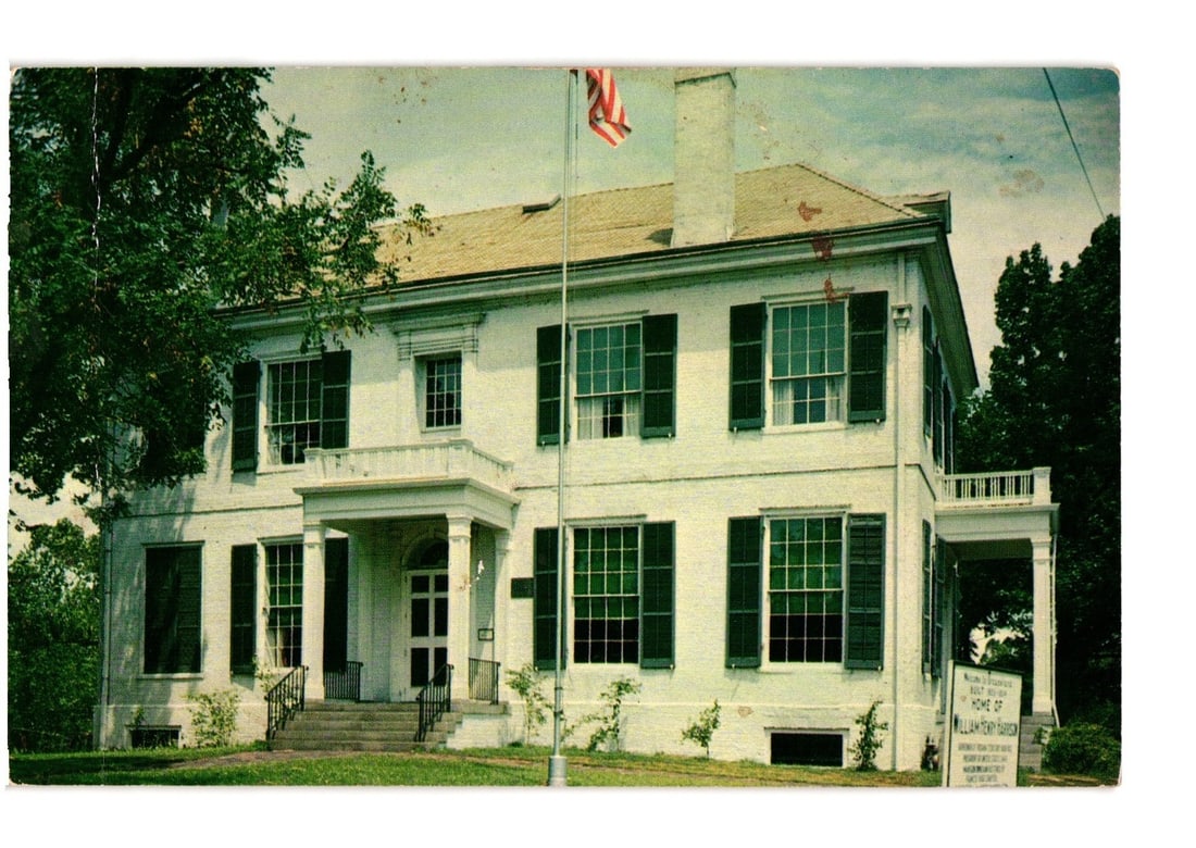 Grouseland, William Henry Harrison Home in Vincennes, Indiana, Mid-20th Century postcard: A grand white two-story building featuring dark green shutters on multiple windows. A central portico entrance with white columns and a balcony on the second story is visible. An American flag flies f