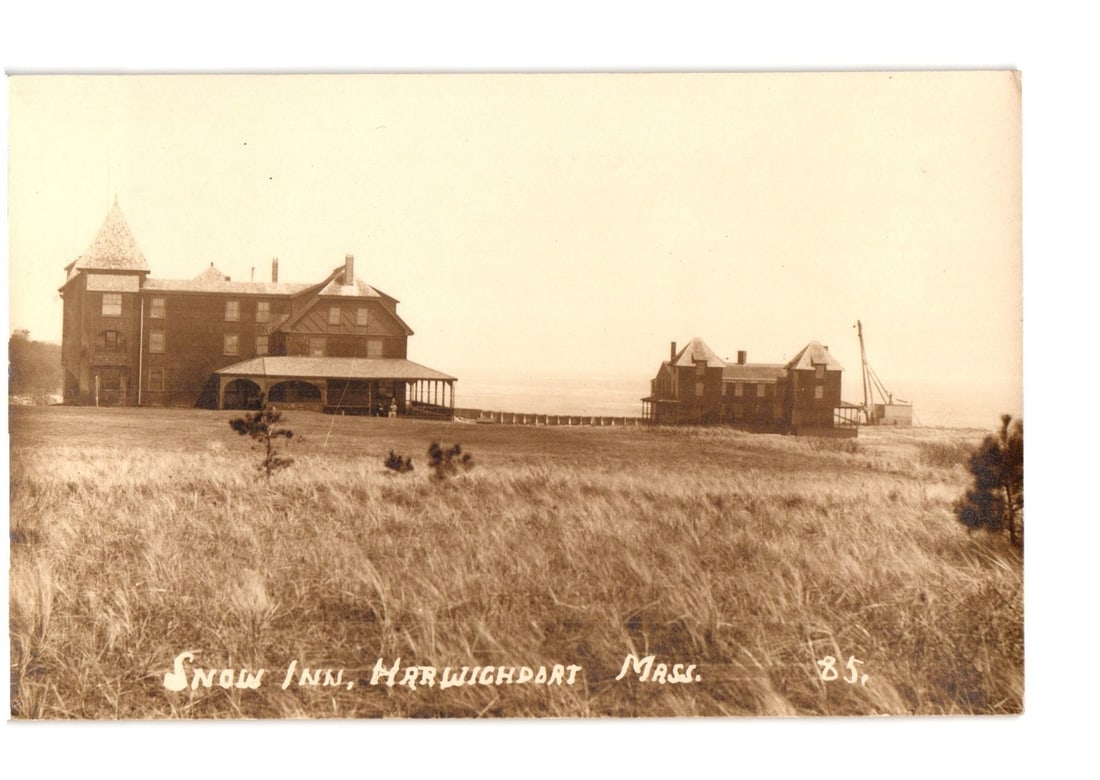 Snow Inn and Coastal Buildings, Harwichport, Massachusetts, early 20th Century postcard: A sepia-toned photograph depicts the Snow Inn, a large multi-story wooden hotel with a conical turret, on the left. A long covered porch extends across the front of the main building. To the right, a 