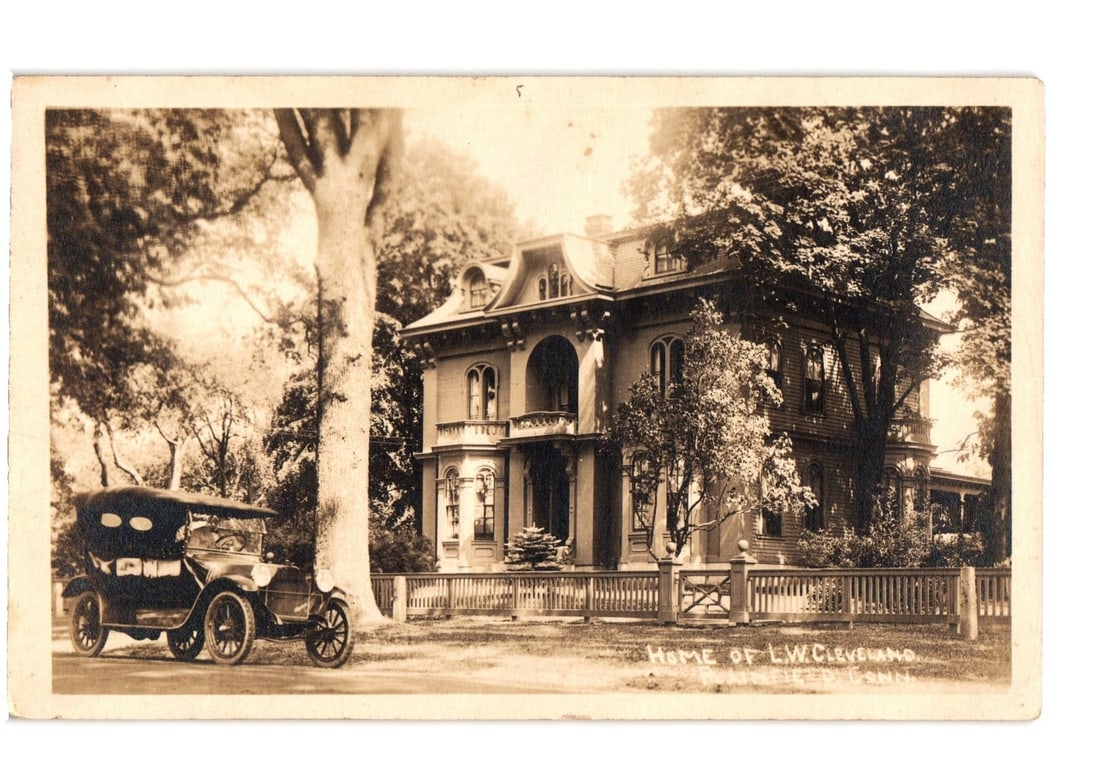 Early 20th Century Shelton, Connecticut postcard featuring the L.W. Cleveland home and an: A large, ornate Victorian-style house is featured, surrounded by mature trees. The house is centrally composed with a three-quarter view showing its left facade and a prominent front porch. An early m