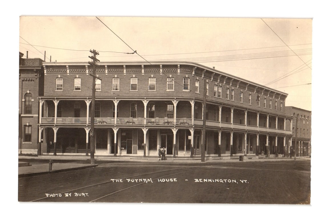 Vintage Real Photo postcard of The Putnam House, a large hotel building in Bennington, Vermont,: A sepia-toned Real Photo postcard depicts The Putnam House, a large three-story brick building, from a street-level perspective. The building features a two-story wrap-around veranda with white pillar