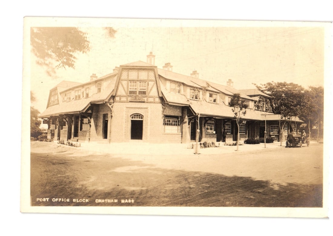 Early 20th Century Real Photo postcard of Post Office Block with car, Chatham, Mass.: A sepia-toned photographic postcard depicts the Post Office Block in Chatham, Massachusetts. The large, multi-story building features a distinctive roofline with numerous dormer windows and an extende