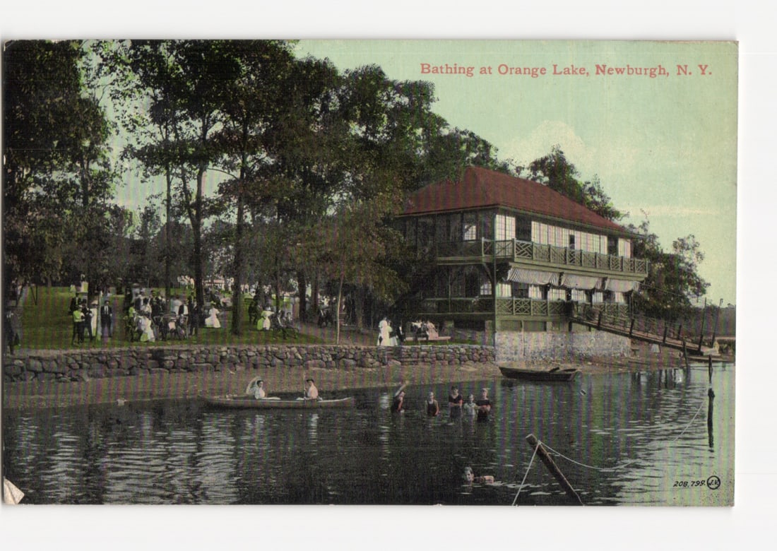 Early 20th-century postcard of bathing and recreation at Orange Lake, Newburgh, New York.: A scenic view depicts people engaging in various recreational activities on Orange Lake. In the foreground, individuals are wading in the water and navigating small boats. The middle ground features a