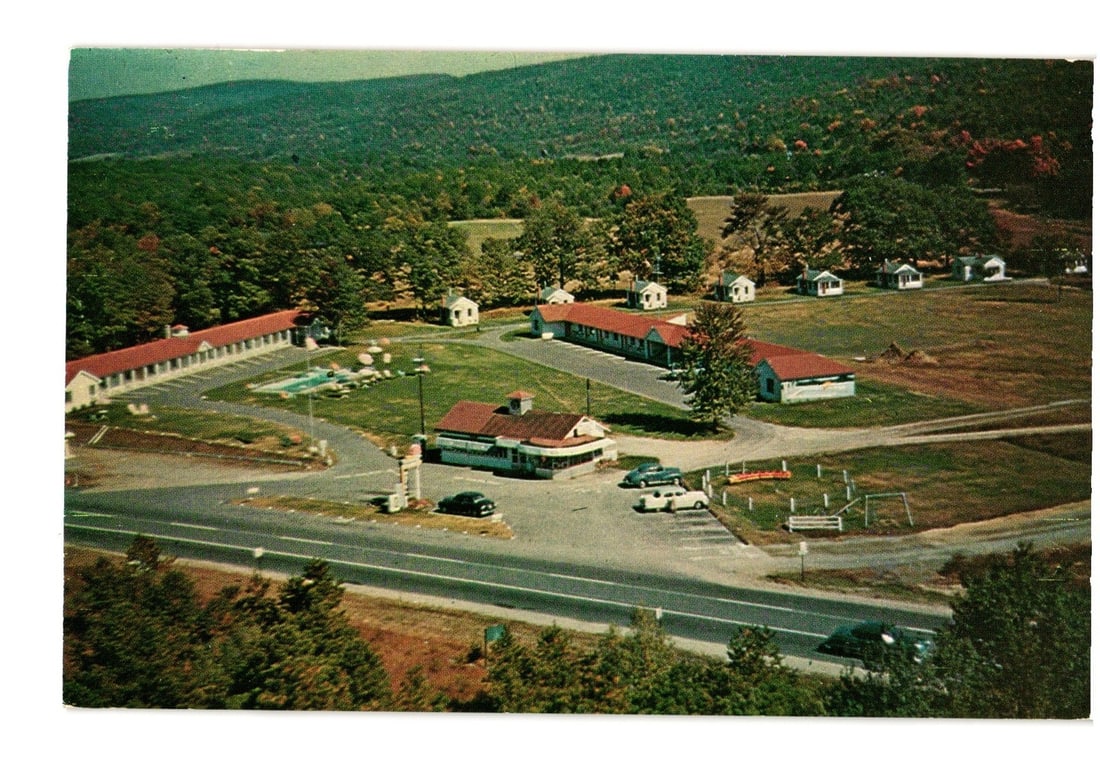 Aerial View Postcard of Weatherhead's Motel and Cabins, Millers Falls, Mass. Mid-20th Century.: An aerial colorchrome view of Weatherhead's Motel and Cabins, depicting the entire complex amidst a forested, hilly landscape. The property features long, low motel buildings and individual cabins, al