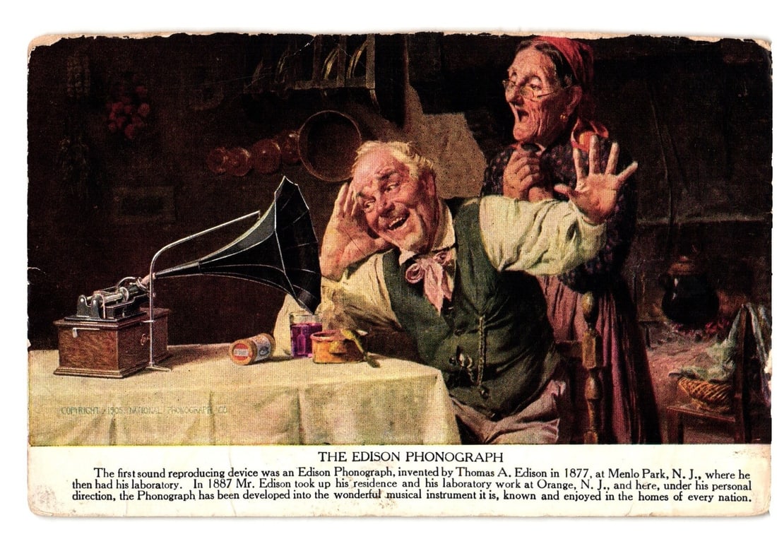 Historical Edison Phonograph Demonstration, Depicting Early Sound Reproduction Postcard: A chromolithograph shows two older individuals reacting to an Edison Phonograph. Grinning man leans to it, hand to ear; an older woman shows surprise with raised hand. The phonograph has a large, dark