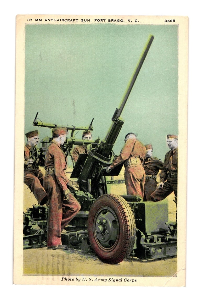 U.S. Army Signal Corps Photograph of 37mm Anti-Aircraft Gun at Fort Bragg, N.C., Mid-20th Century: Six uniformed soldiers are positioned around a large 37mm anti-aircraft gun, mounted on a wheeled carriage, with its barrel elevated. The gun is centrally located in the composition. The background fe