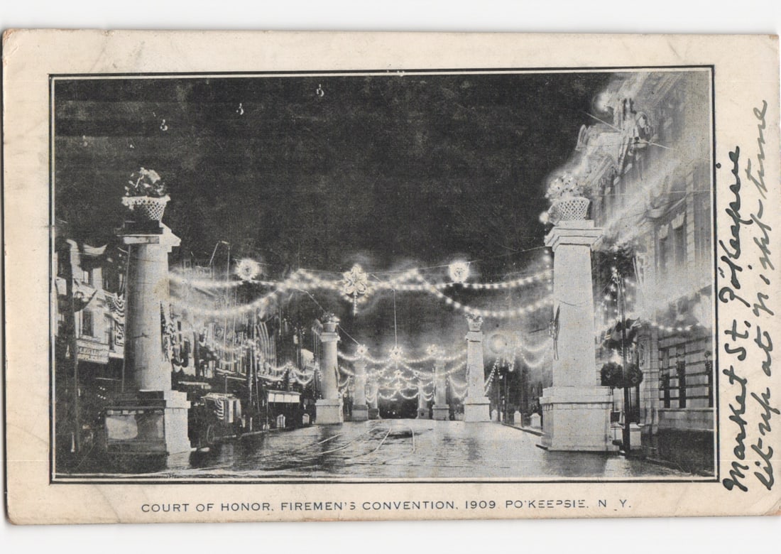 Poughkeepsie, N.Y. Firemen's Convention 1909 'Court of Honor' Market Street Illuminated Postcard: Night scene of Market Street in Poughkeepsie, N.Y., decorated for a Firemen's Convention in 1909. The street is lined with multiple tall, classical pillars topped with decorative urns or lamps, strung