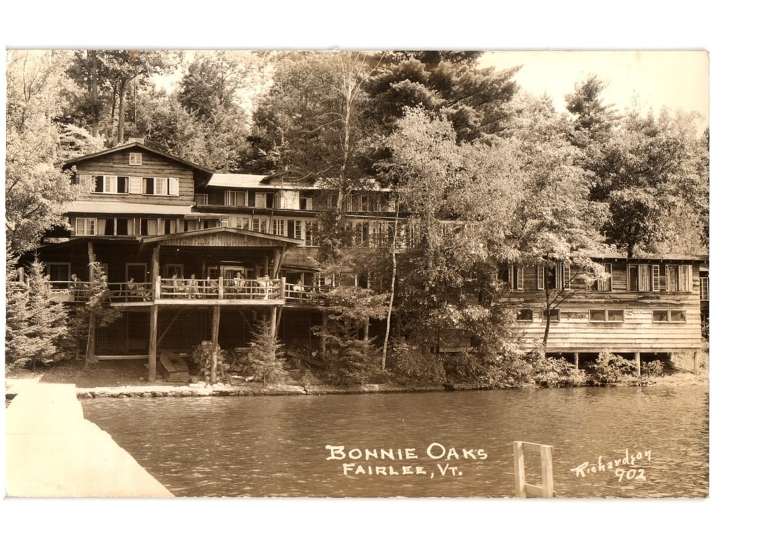 Bonnie Oaks Lodge on the Lake, Fairlee, Vermont, 1941 vintage photographic postcard: A photographic view of Bonnie Oaks, a multi-story lodge or hotel, situated by a body of water. The wooden structure features several balconies and porches, with dense forest surrounding the building. 