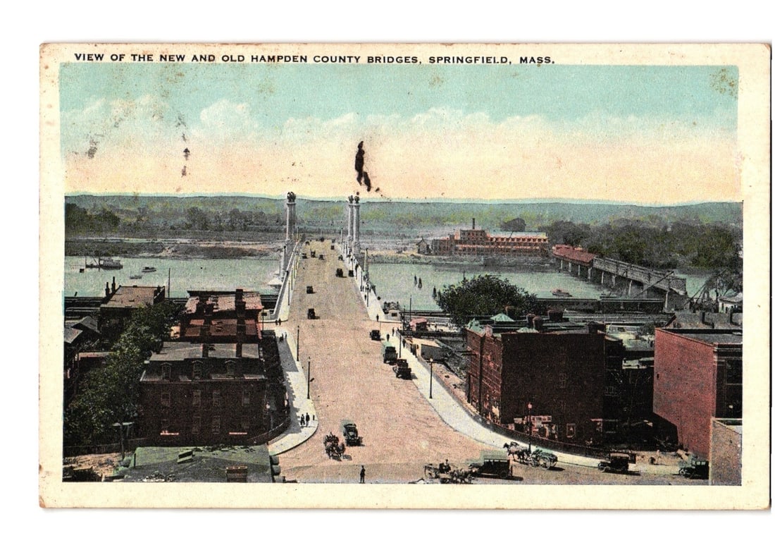 Early 20th Century Chromolithograph Postcard of New and Old Hampden County Bridges, Springfield,: An elevated, wide-angle view depicts the cityscape of Springfield, Massachusetts, with a focus on two prominent bridges spanning a river. In the foreground, a busy road ascends toward the bridges, fea