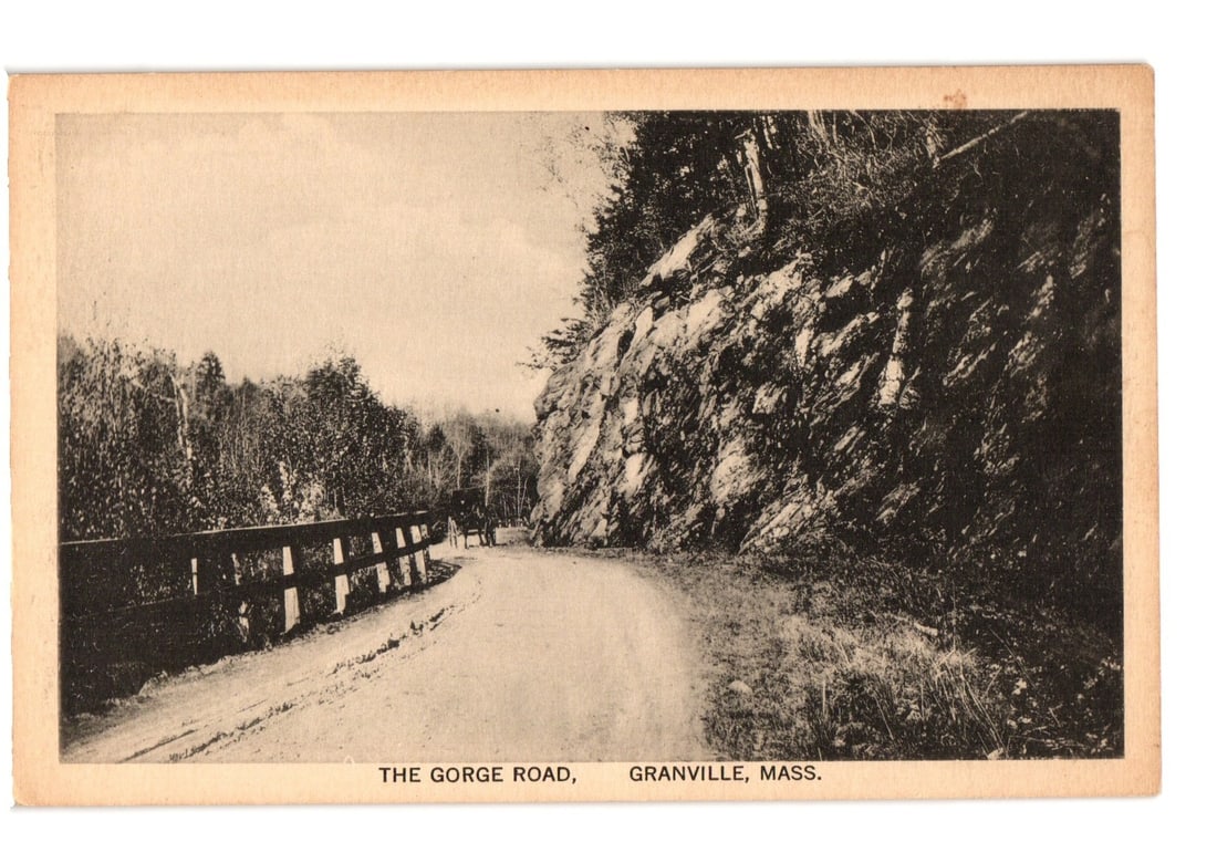 The Gorge Road, Granville, Mass. Early 20th Century Landscape View Postcard: A sepia-toned landscape depicts a winding dirt road leading into the distance. On the left, a wooden fence parallels the road, beyond which a dense forest of deciduous and evergreen trees extends. The