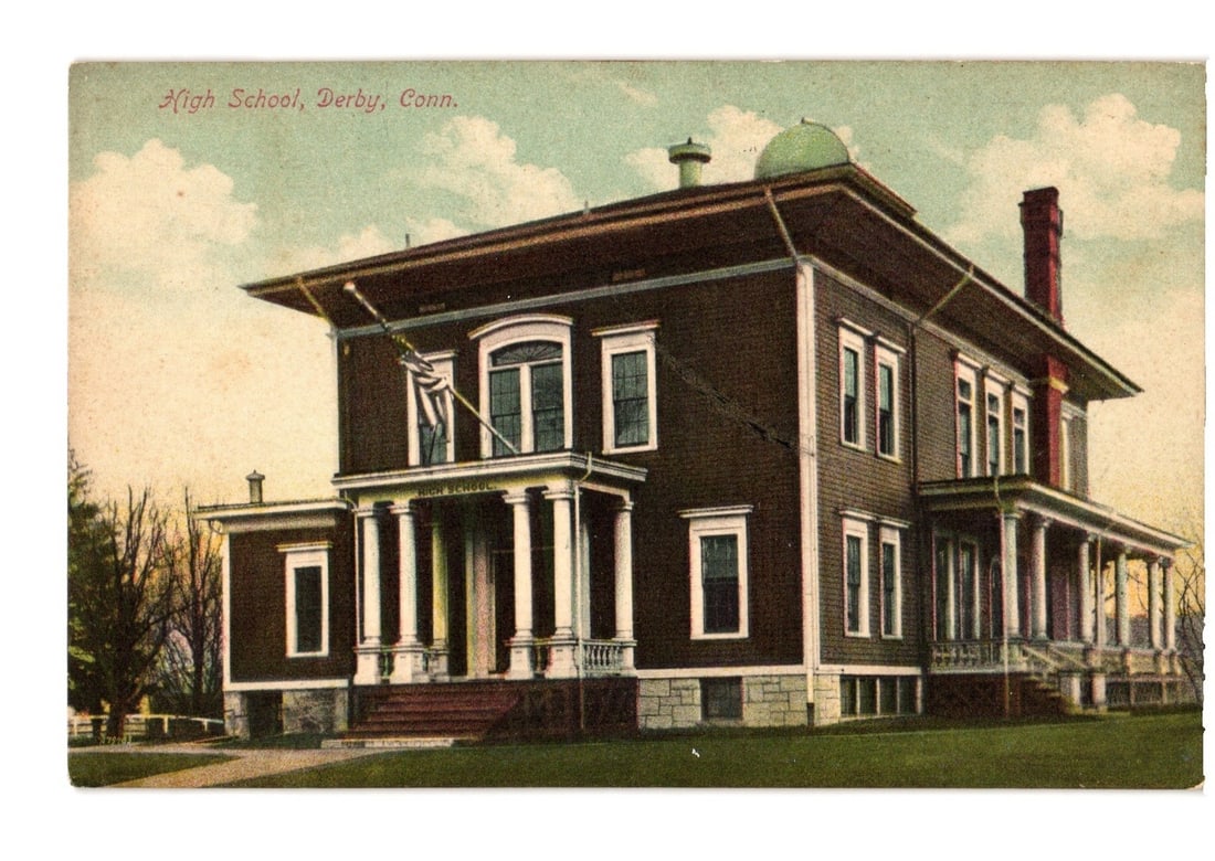 High School Building in Derby, Connecticut - Early 20th Century Colorized Lithograph Postcard: A large, multi-story institutional building, identified as a high school, dominates the scene. The structure features a prominent columned portico entrance with a balustrade, multiple windows, and a w