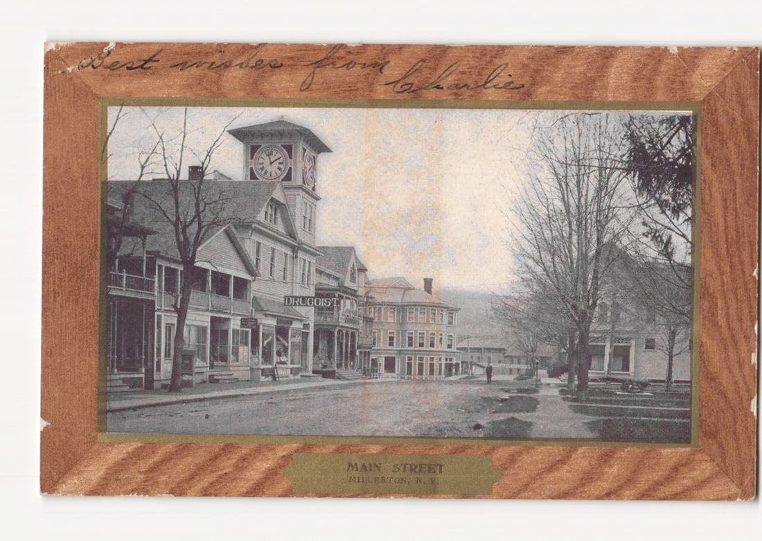 Main Street, Millerton, N.Y. with Clock Tower and Buildings, early 20th Century photochrome postcard: A street view depicts Main Street in Millerton, N.Y., featuring a prominent clock tower building at the center left. Several multi-story commercial buildings line the street, including one with "DRUGG