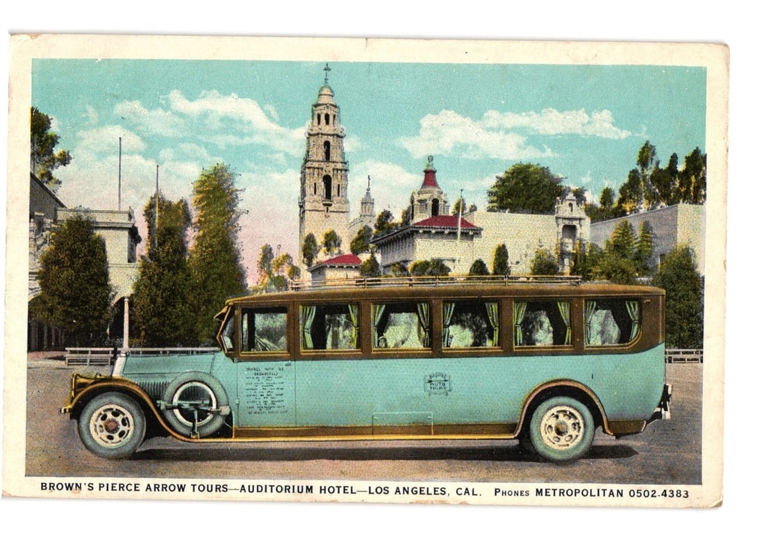 Vintage Pierce Arrow Tour Bus, Los Angeles Auditorium Hotel, 1930s era postcard.: A large, vintage touring bus, identified as a Pierce Arrow, is depicted in profile, facing left. The bus has a light blue/teal body with brown trim and roof, featuring multiple passenger windows with 