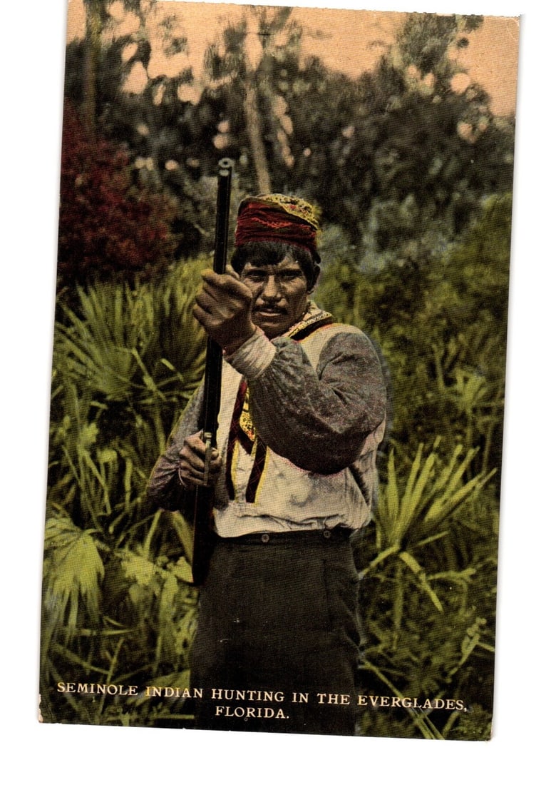 Vintage Florida postcard of a Seminole Indian man with rifle in the Everglades, early 20th century. (1 of 2)