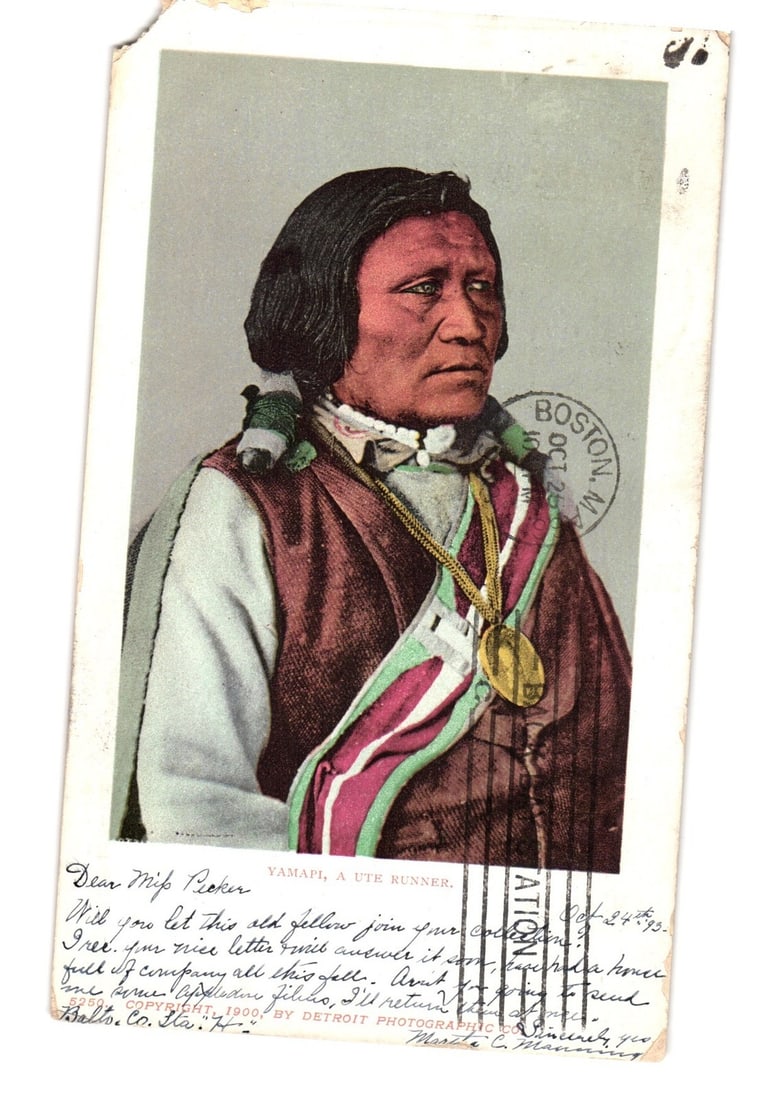 YAMAPI, A UTE RUNNER Indigenous Man Portrait Postcard, Hand-Colored, Circa 1900s.: A hand-colored portrait depicts Yamapi, a Ute man, from the waist up. He wears a dark vest over a lighter tunic, accented by a striped sash with green and maroon elements over his left shoulder. A lar