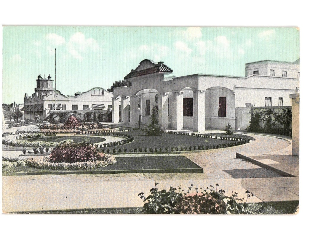 Colorized postcard of the General View of Universal City, California, Administration Building and: A colorized photographic print depicts the approach to Universal City, California. The image features a large architectural complex with a central building distinguished by a tiled roof and an arched 