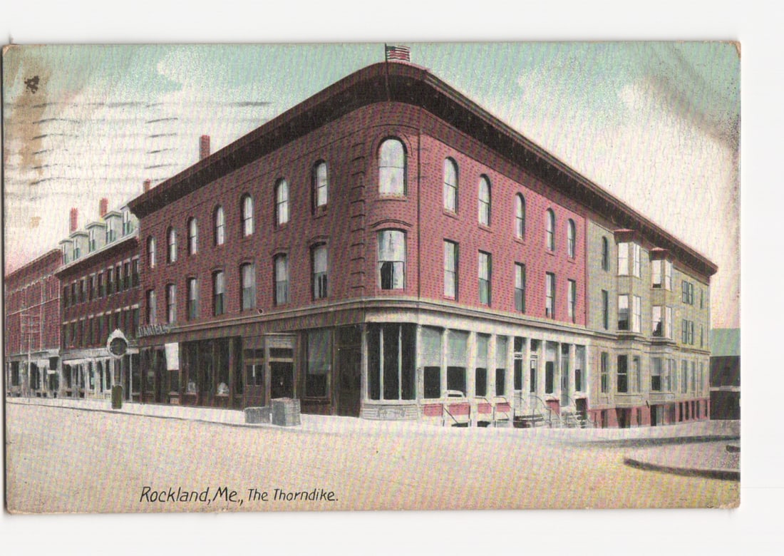The Thorndike, a prominent early 20th-century architectural building postcard from Rockland, Maine.: A multi-story brick building, identified as "The Thorndike," stands at a street intersection, featuring a distinctive rounded corner. The building is constructed of red brick with multiple floors, dis